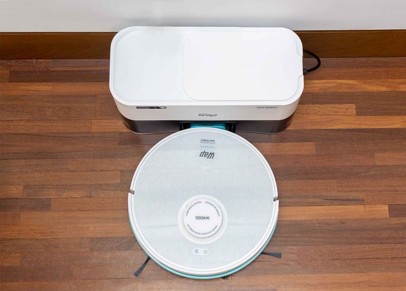 robo-aspirador-w4000-branco-com-uma-visao-de-cima-em-um-piso-de-madeira-marrom-com-a-base-de-limpeza-branca-vista-de-cima-7899831332656-7899831332670